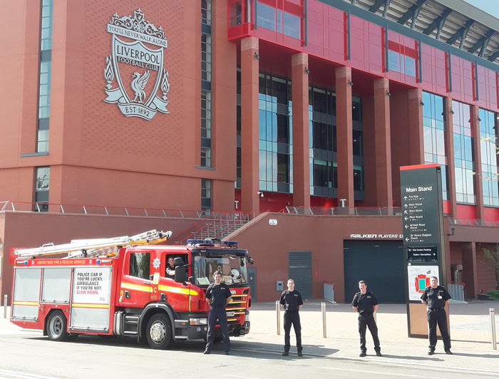 Fire engine and fire fighters posed outside Liverpool FC's stadium
